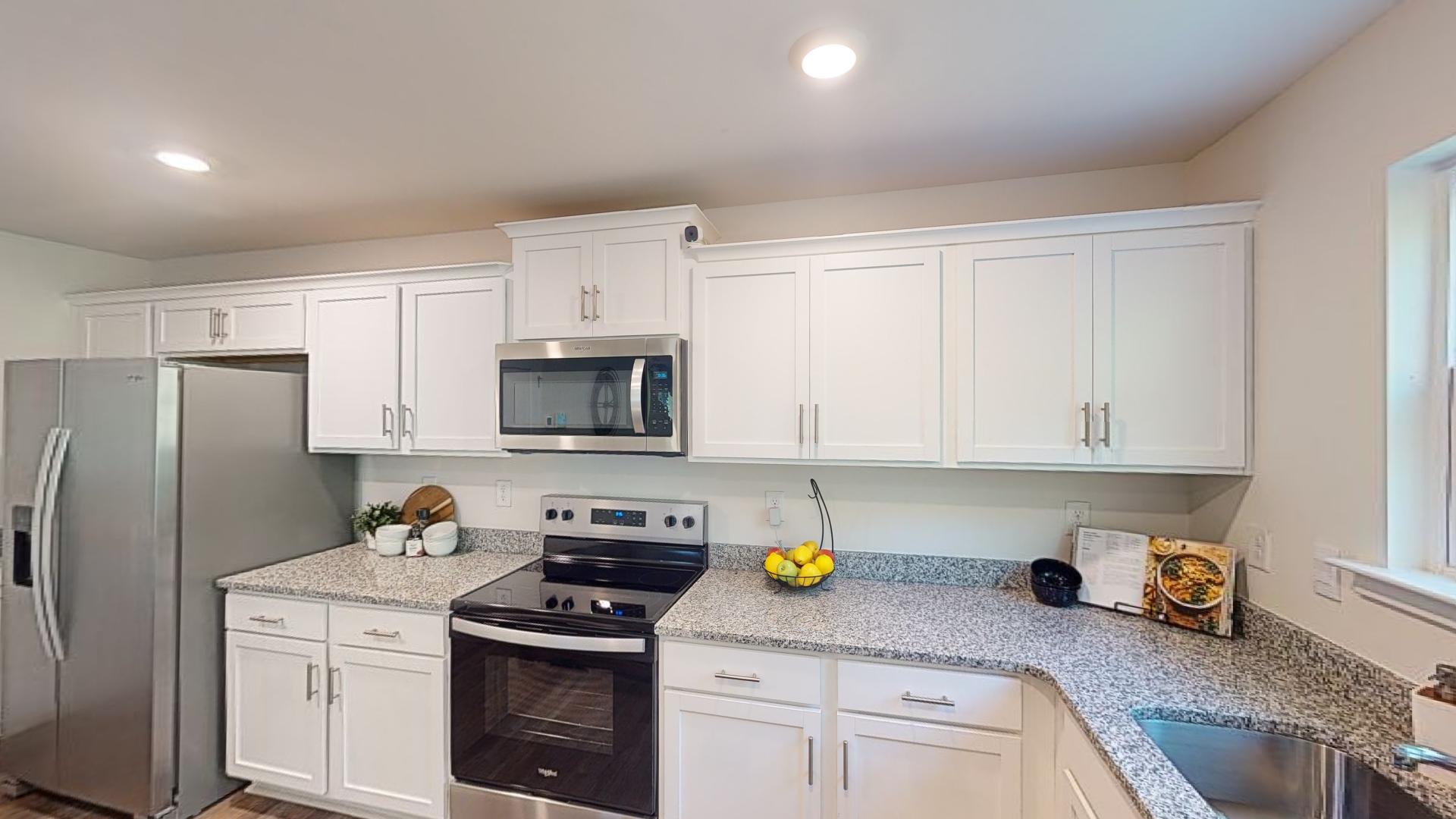 Kitchen and island with white cabinets, tile backsplash and stainless steel appliances