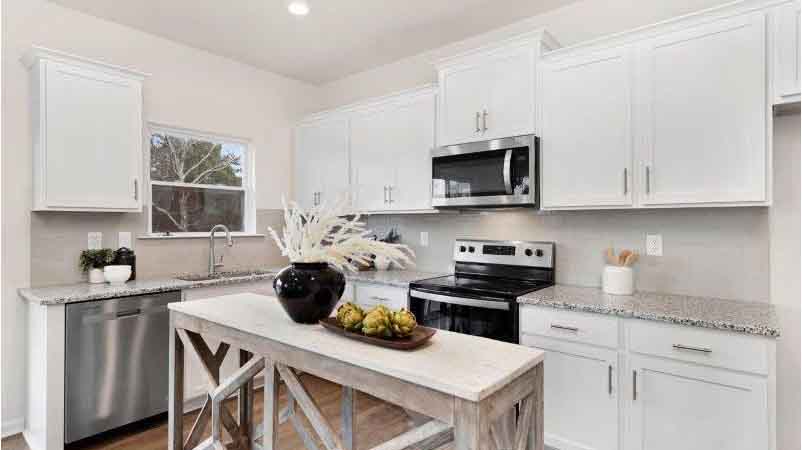 Kitchen and island with white cabinets, tile backsplash and stainless steel appliances