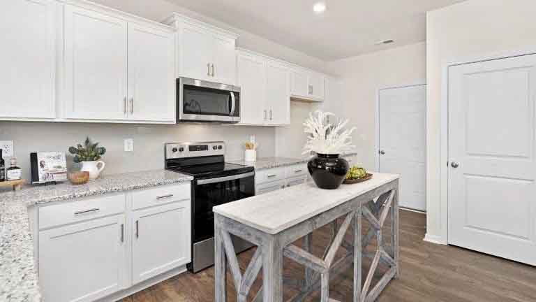 Kitchen and island with white cabinets, tile backsplash and stainless steel appliances
