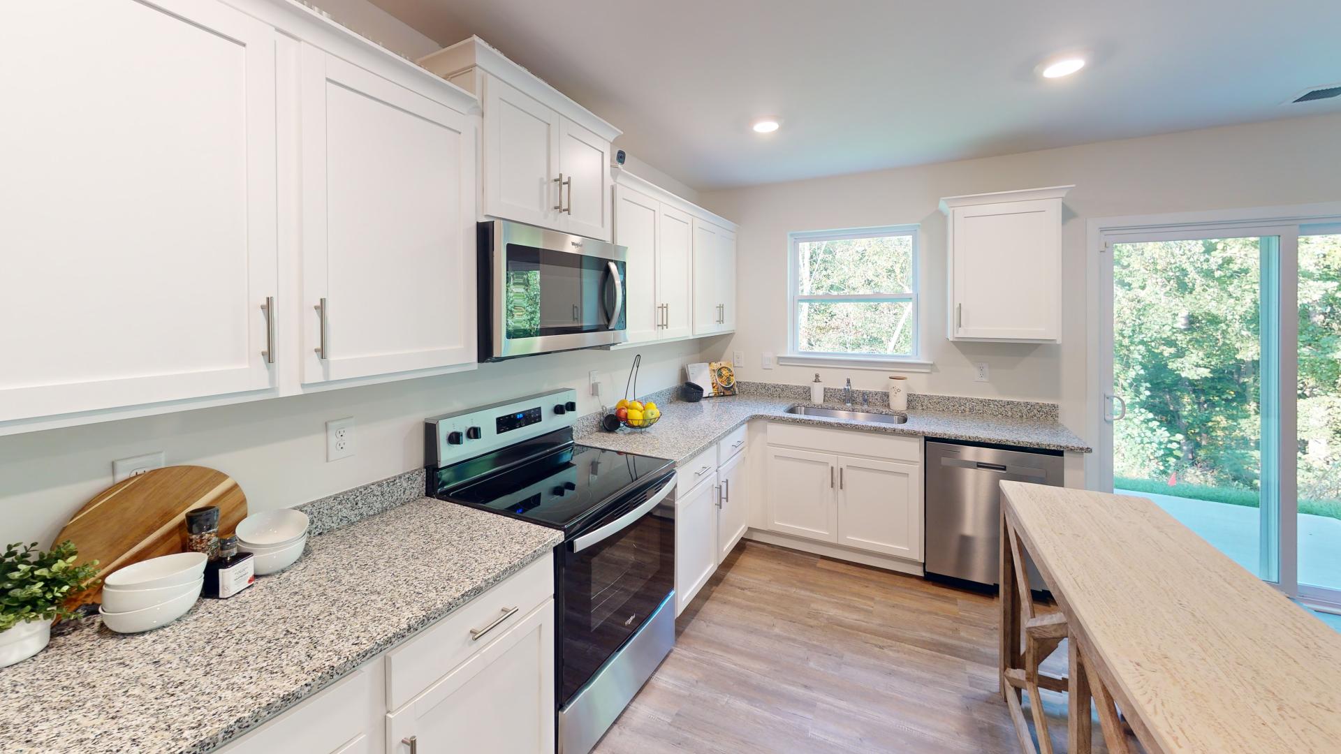 Kitchen and island with white cabinets, tile backsplash and stainless steel appliances