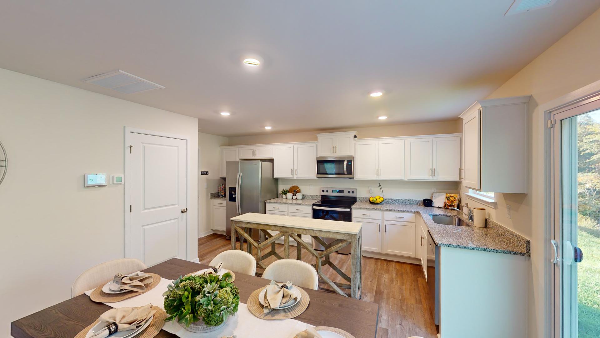 Kitchen and island with white cabinets, tile backsplash and stainless steel appliances