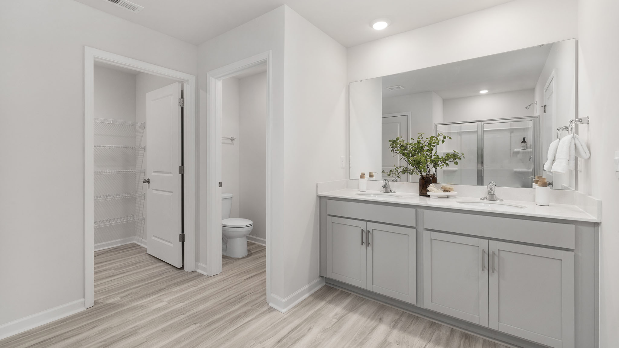 Primary bathroom with double sinks, white cabinets and counters