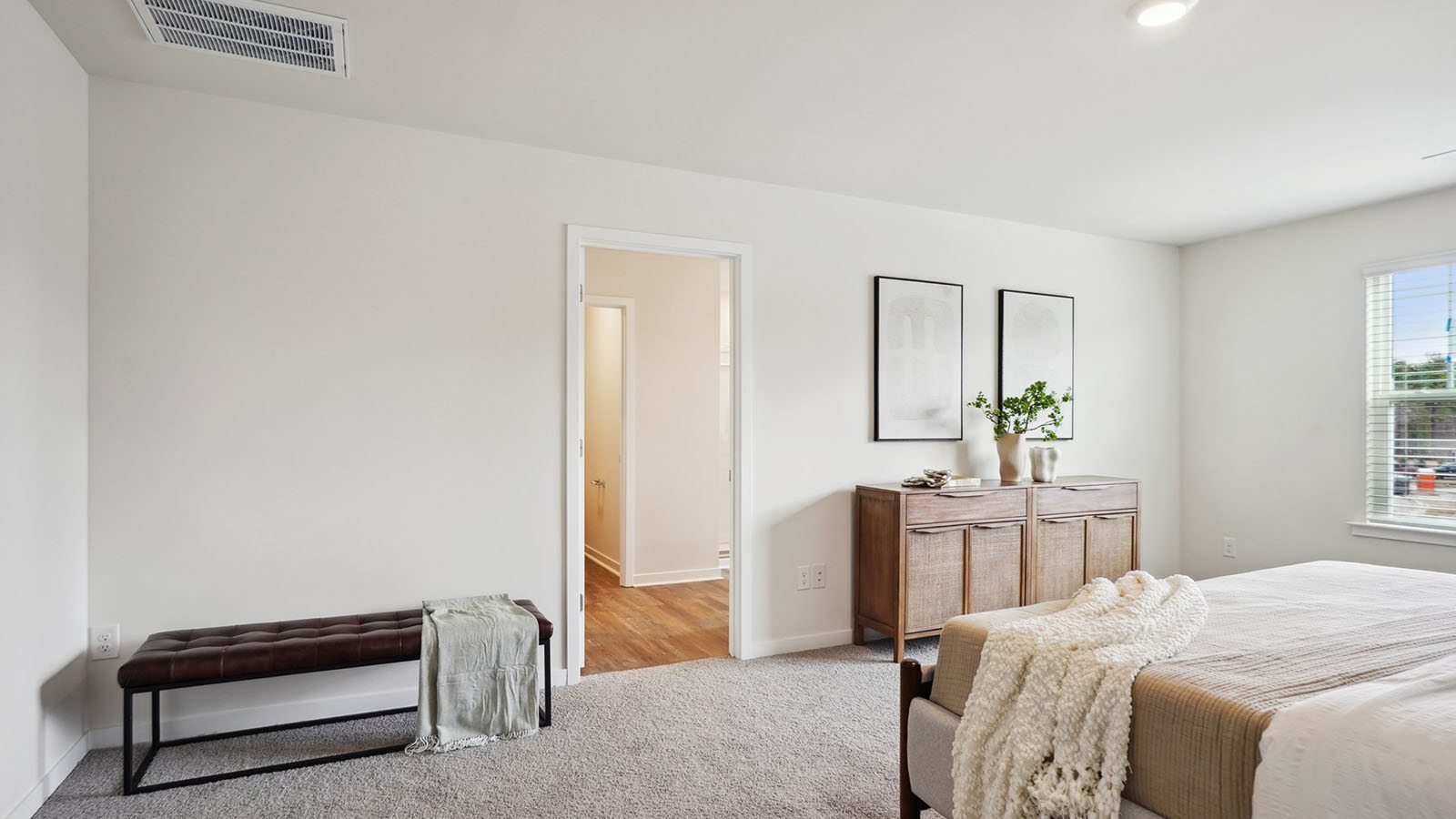 Model primary carpeted bedroom with large window