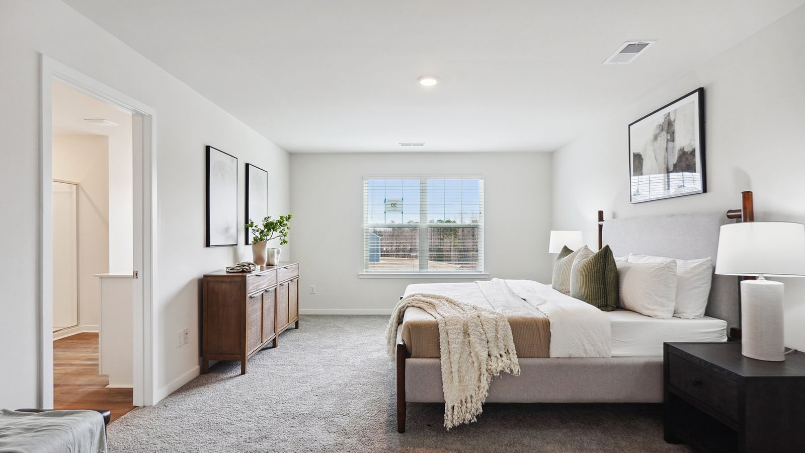 Model primary carpeted bedroom with large window