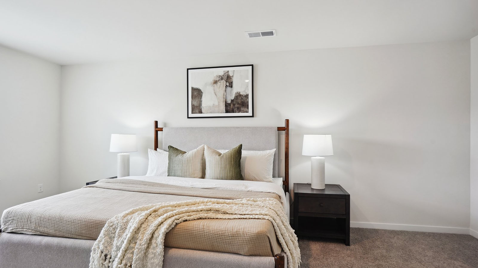 Model primary carpeted bedroom with large window