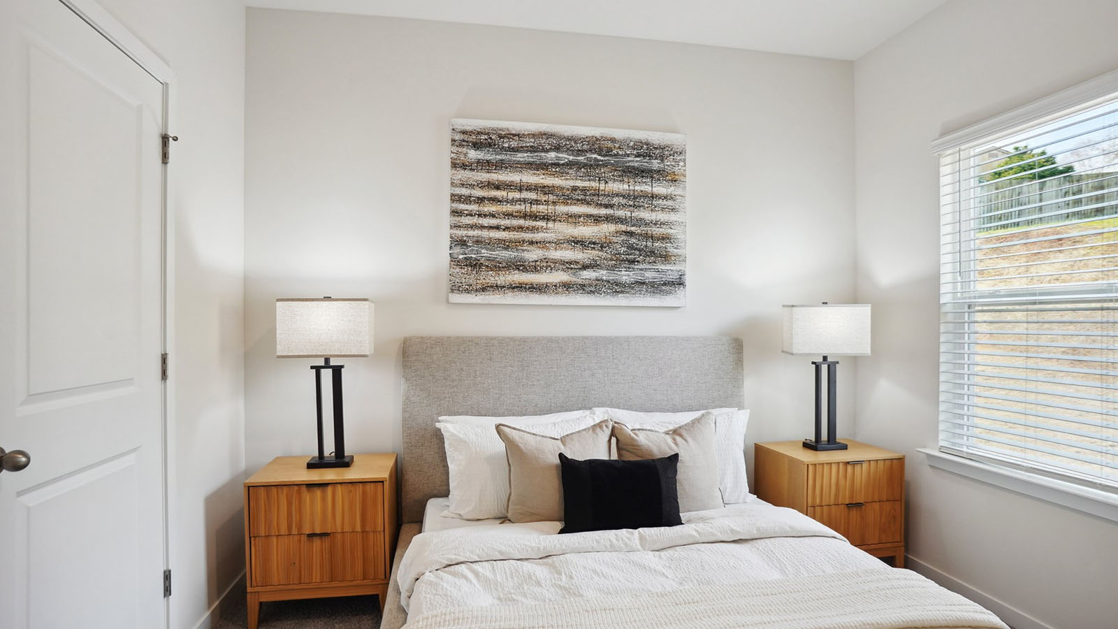 Model primary carpeted bedroom with large window