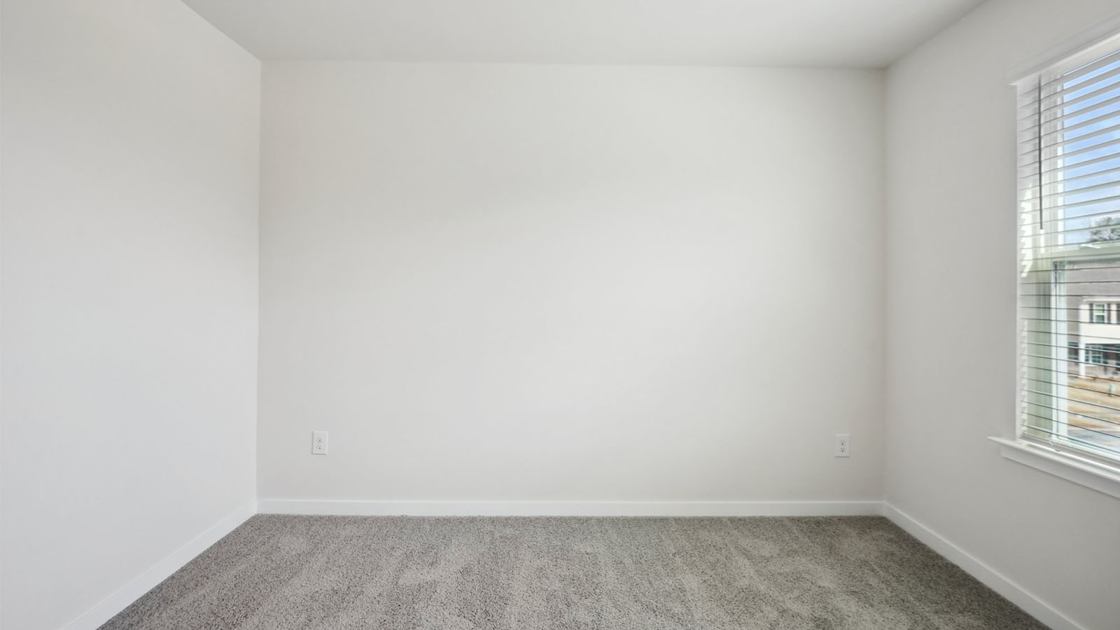 Model carpeted bedroom with small window