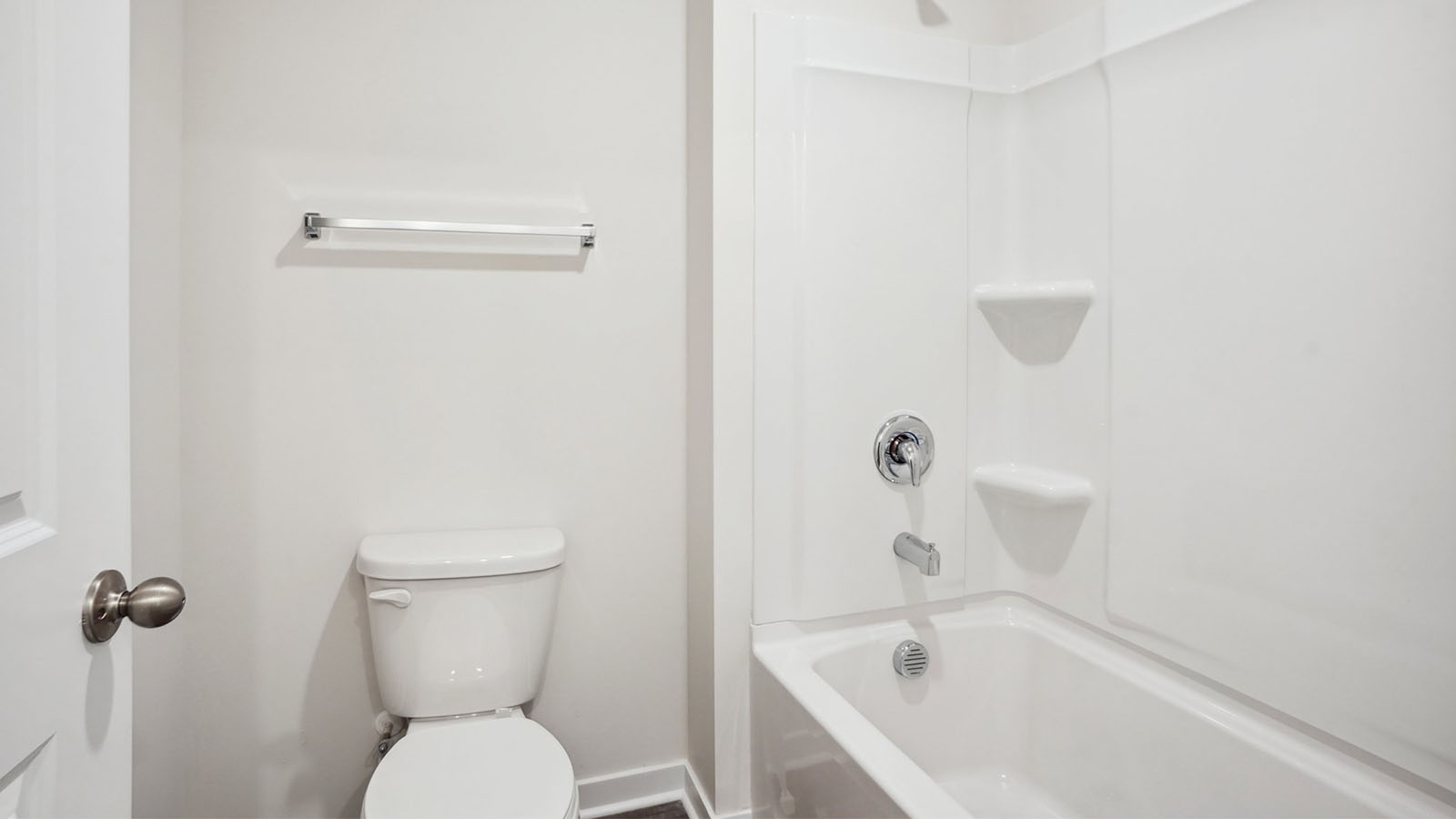 Model bathroom with white counters and cabinets, double sinks and glass door shower
