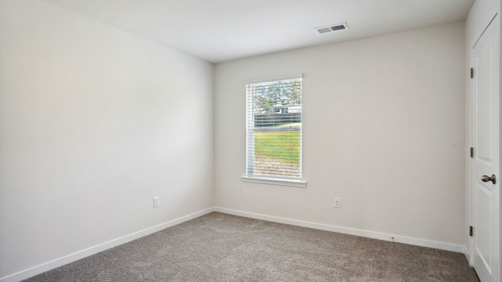 Model carpeted bedroom with small window