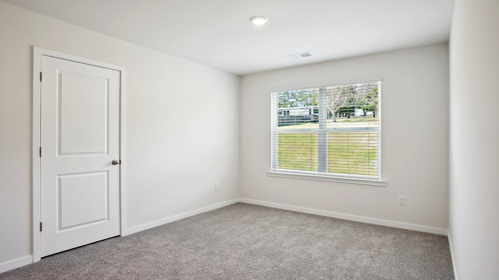 Model carpeted bedroom with small window