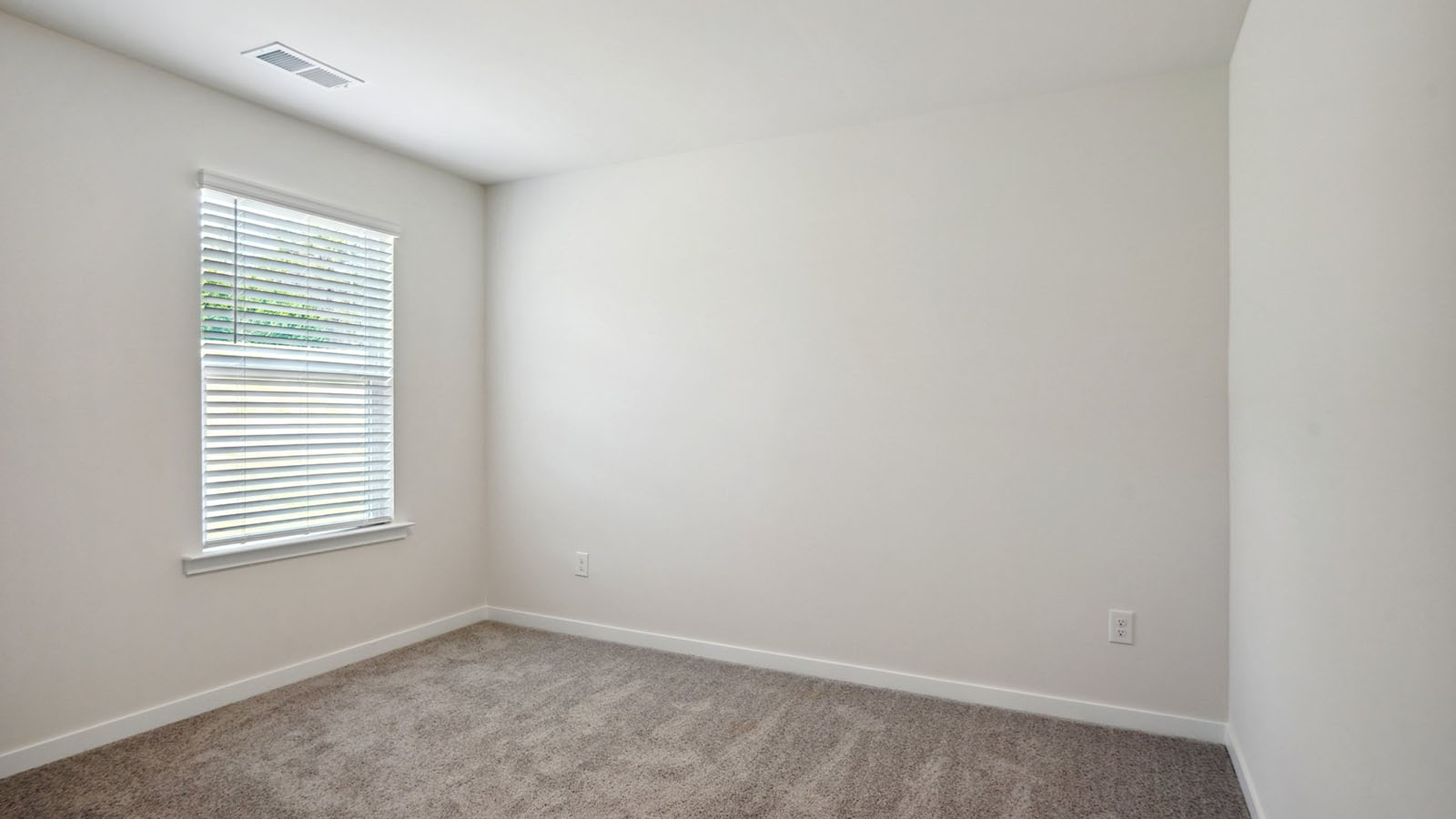 Model carpeted bedroom with small window