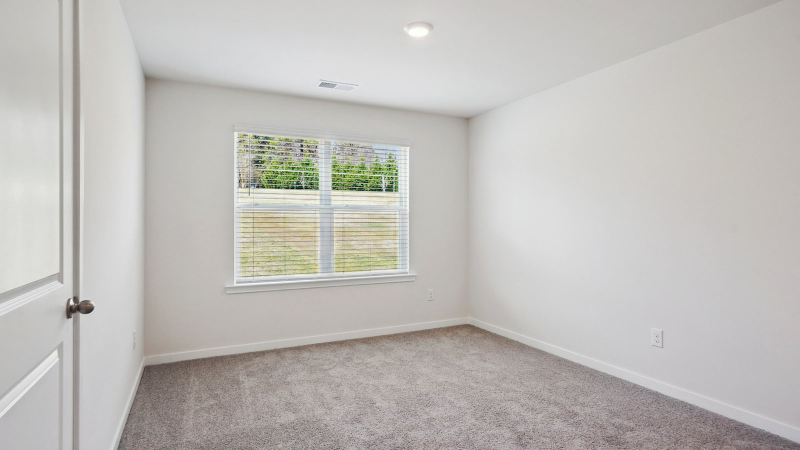 Model carpeted bedroom with small window
