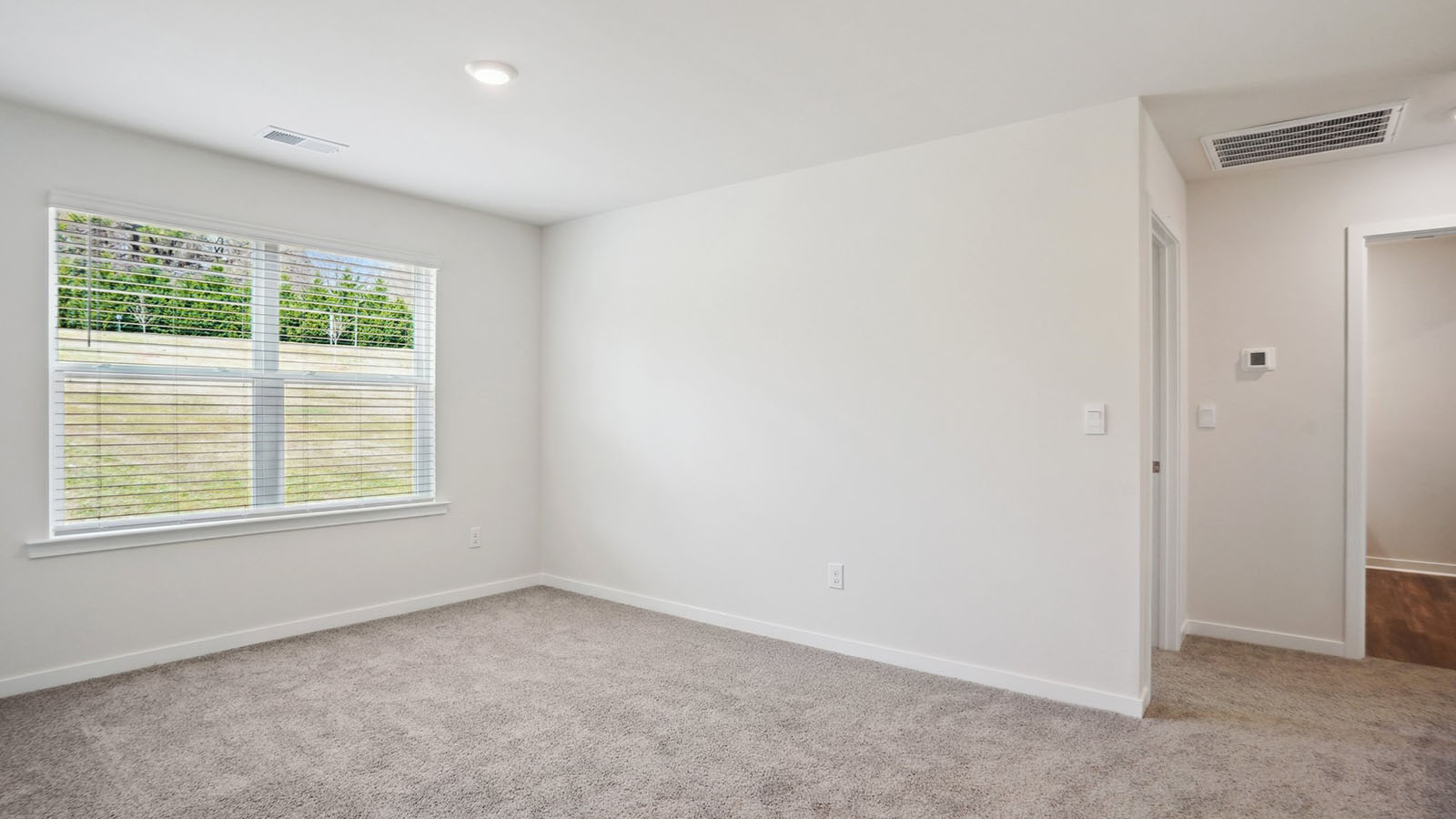 Model carpeted bedroom with small window