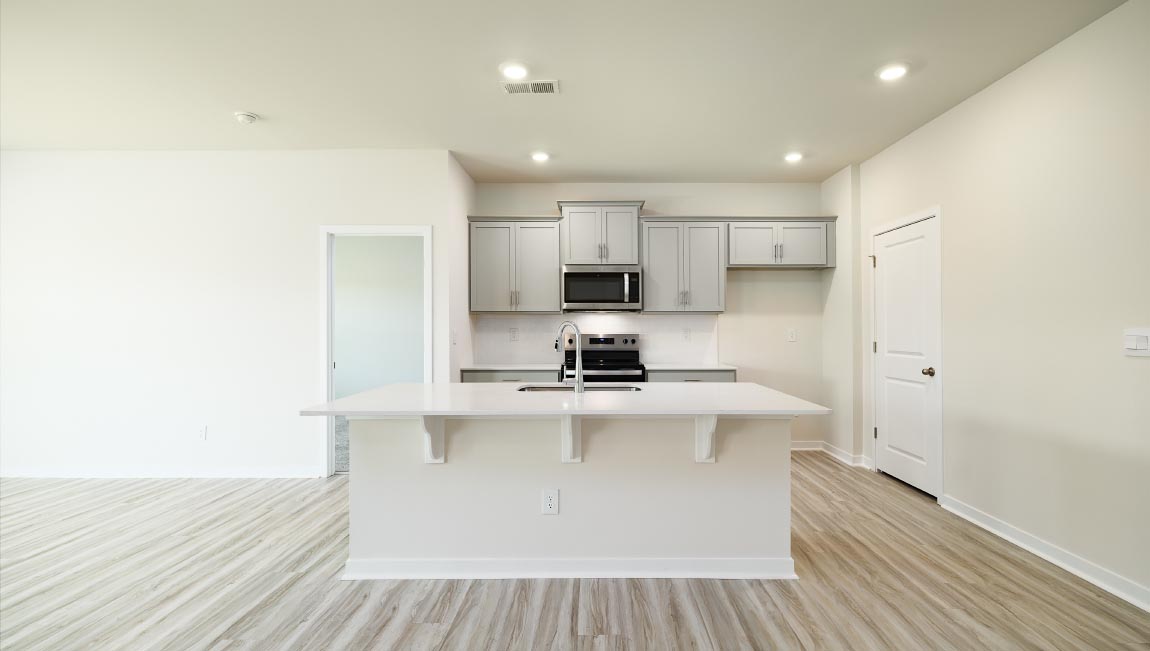 Kitchen and island with white cabinets, quarts countertops, wood floors, and stainless steel appliances