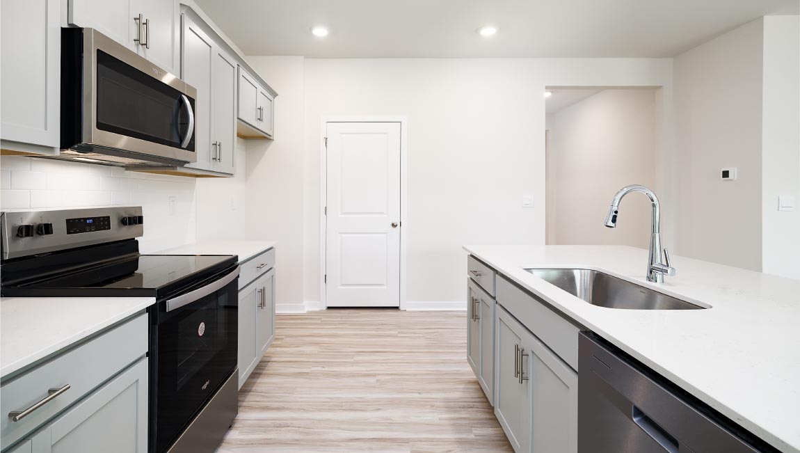 Kitchen and island with white cabinets, quarts countertops, wood floors, and stainless steel appliances