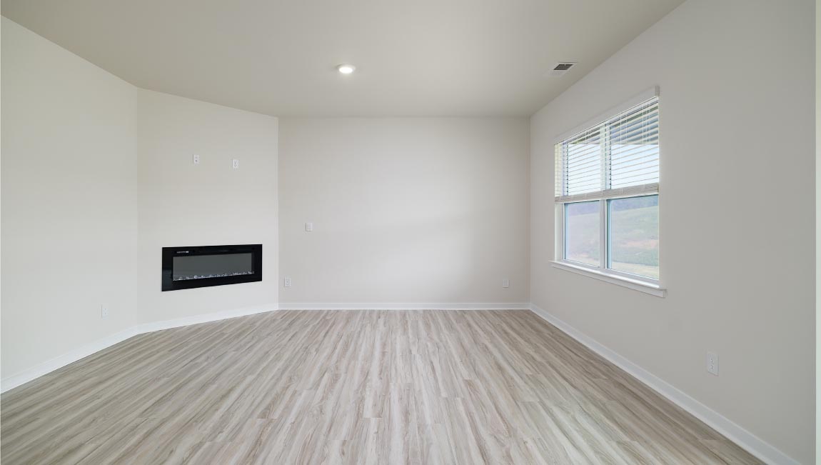 Modern open-concept living room with wood floors, and a fireplace, located beside kitchen