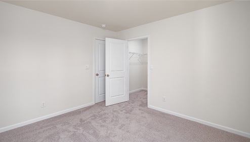 Carpeted bedroom  with small window, view of entry door