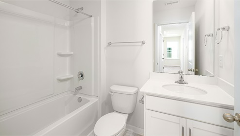 Bathroom with white counters and cabinets, and bathtub