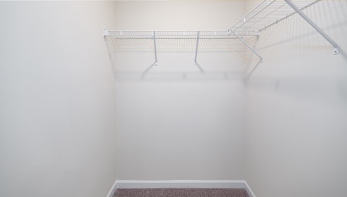 Carpeted walk in closet with built in racks for hanging
