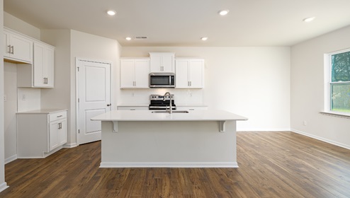 Kitchen and island with white cabinets, quartz counters, wood floors and stainless steel appliances