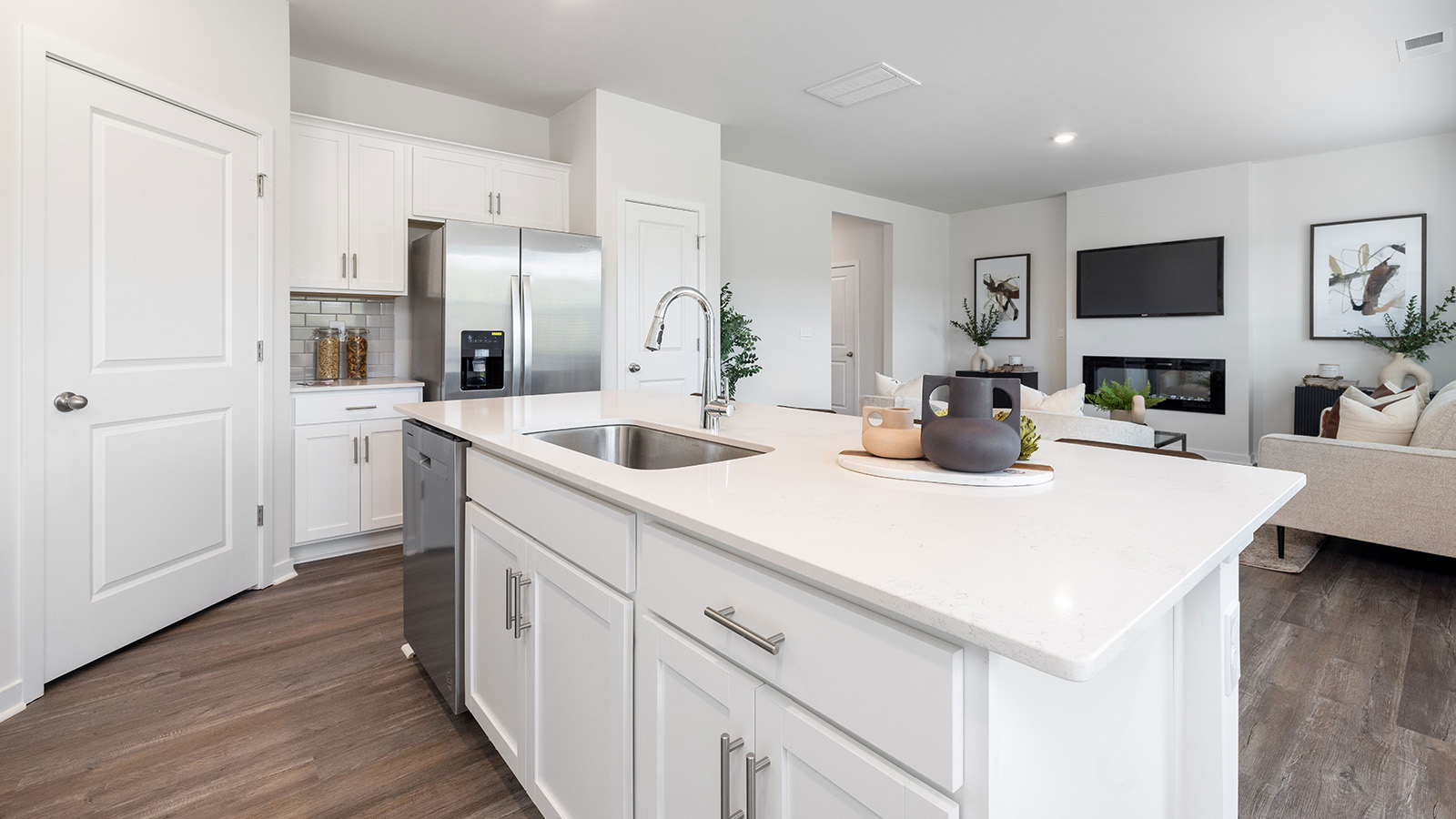 Kitchen and island with white cabinets, quartz counters, wood floors and stainless steel appliances