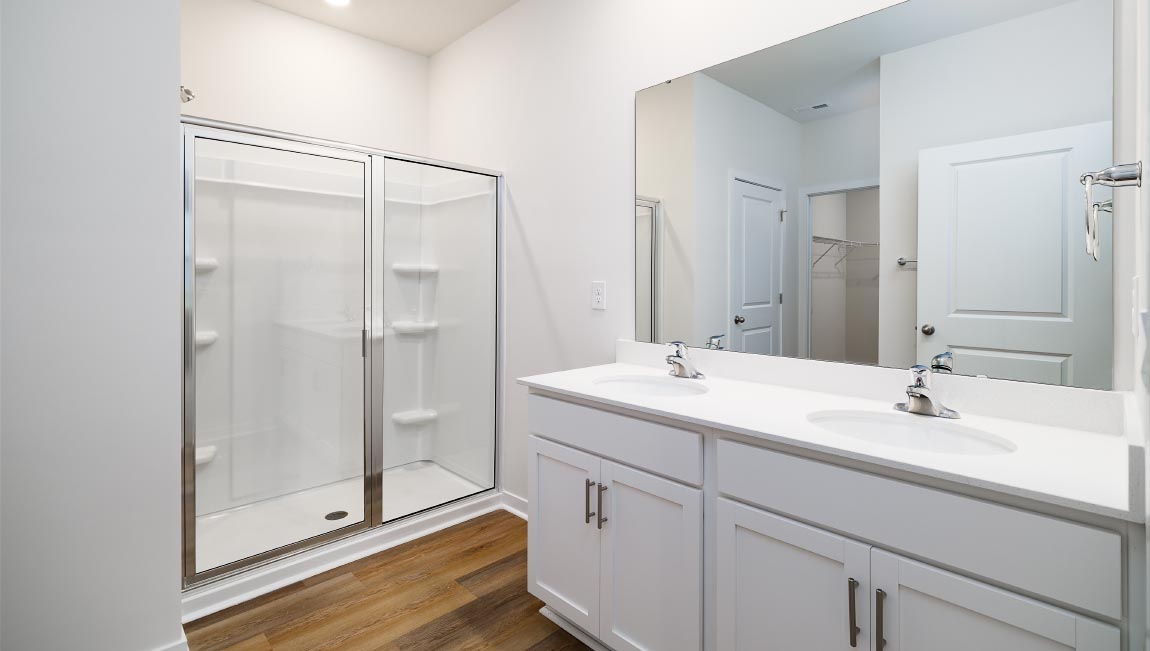 Bathroom with white cabinets and counters, and glass door shower