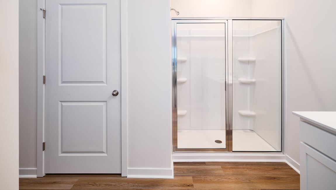Bathroom with white cabinets and counters, and glass door shower