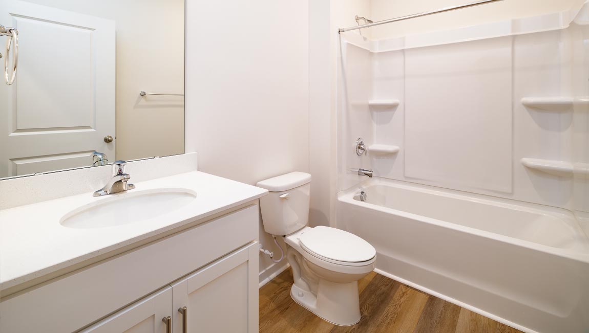Bathroom with white cabinets and counters, and glass door shower