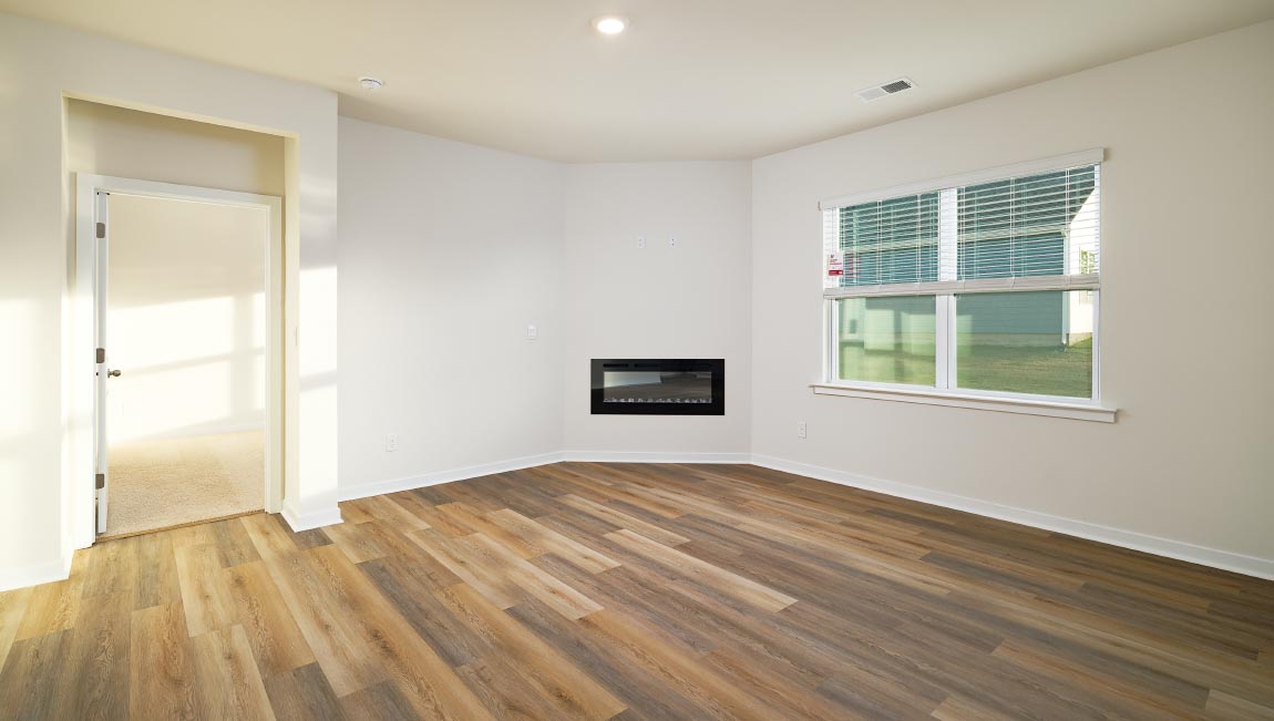 Open living room with wood floors, large window, and fireplace