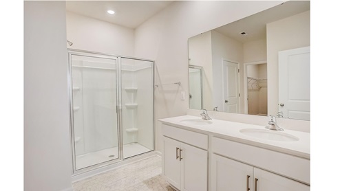 Bathroom with white cabinets and counters, and glass door shower