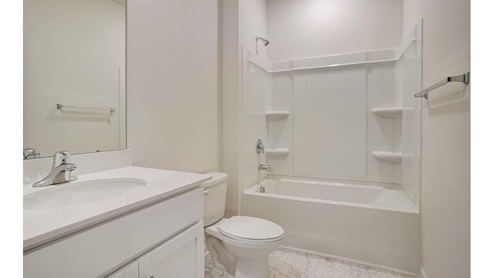 Bathroom with white cabinets and counters, and bathtub