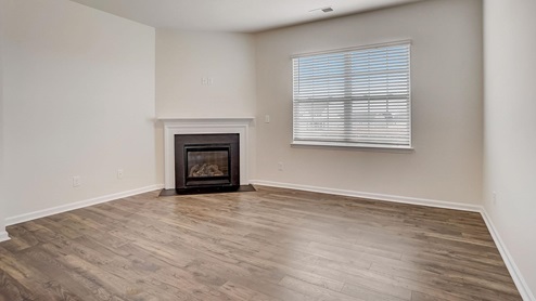 Open living room with wood floors, large window, and fireplace