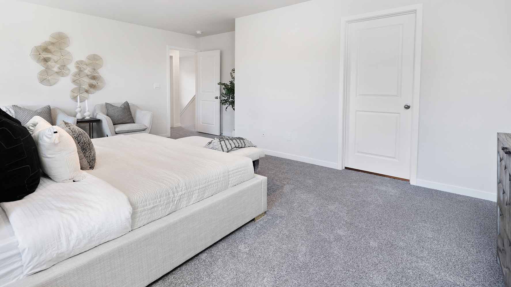 Primary bedroom with carpet and view of bathroom door and entryway door