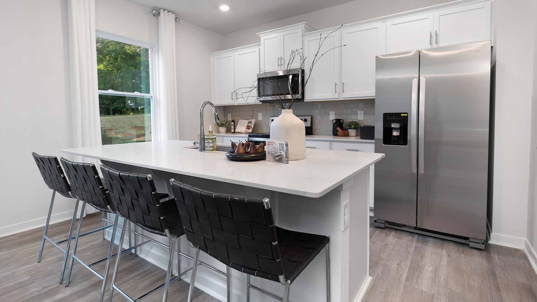 Kitchen and island with white cabinets and counters, wood floors and stainless steel appliances