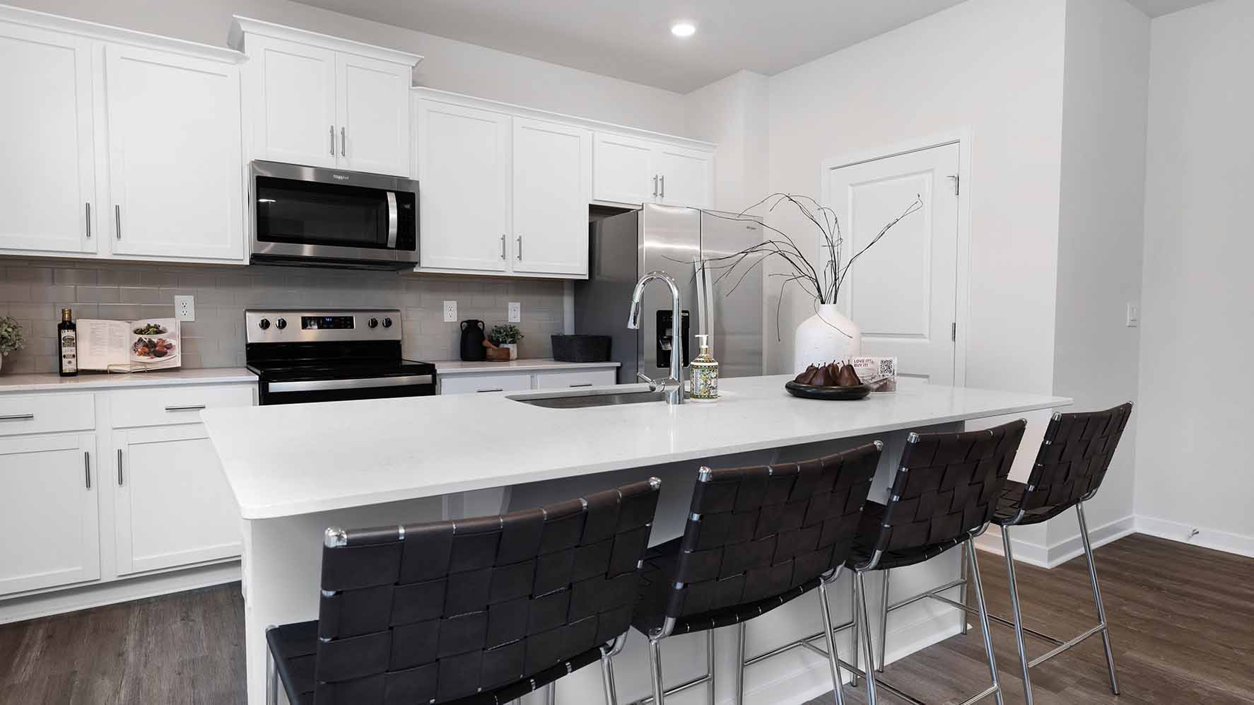 Kitchen and island with white cabinets and counters, wood floors and stainless steel appliances