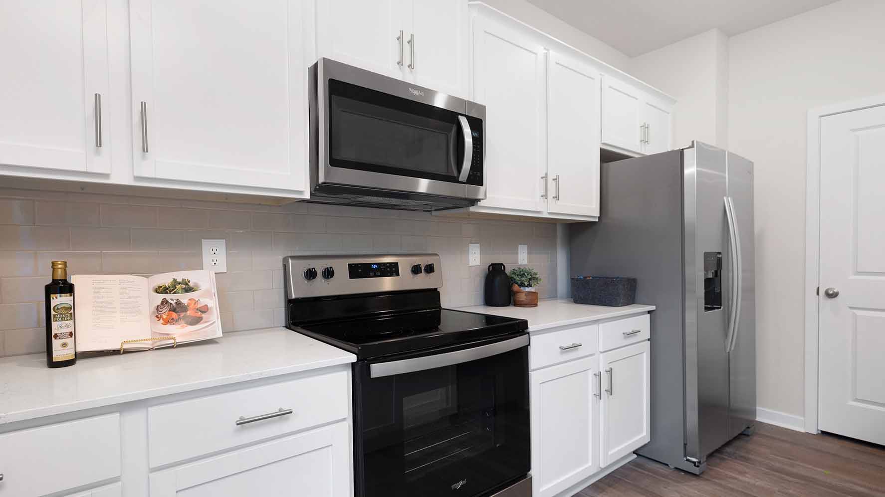 Kitchen and island with white cabinets and counters, wood floors and stainless steel appliances