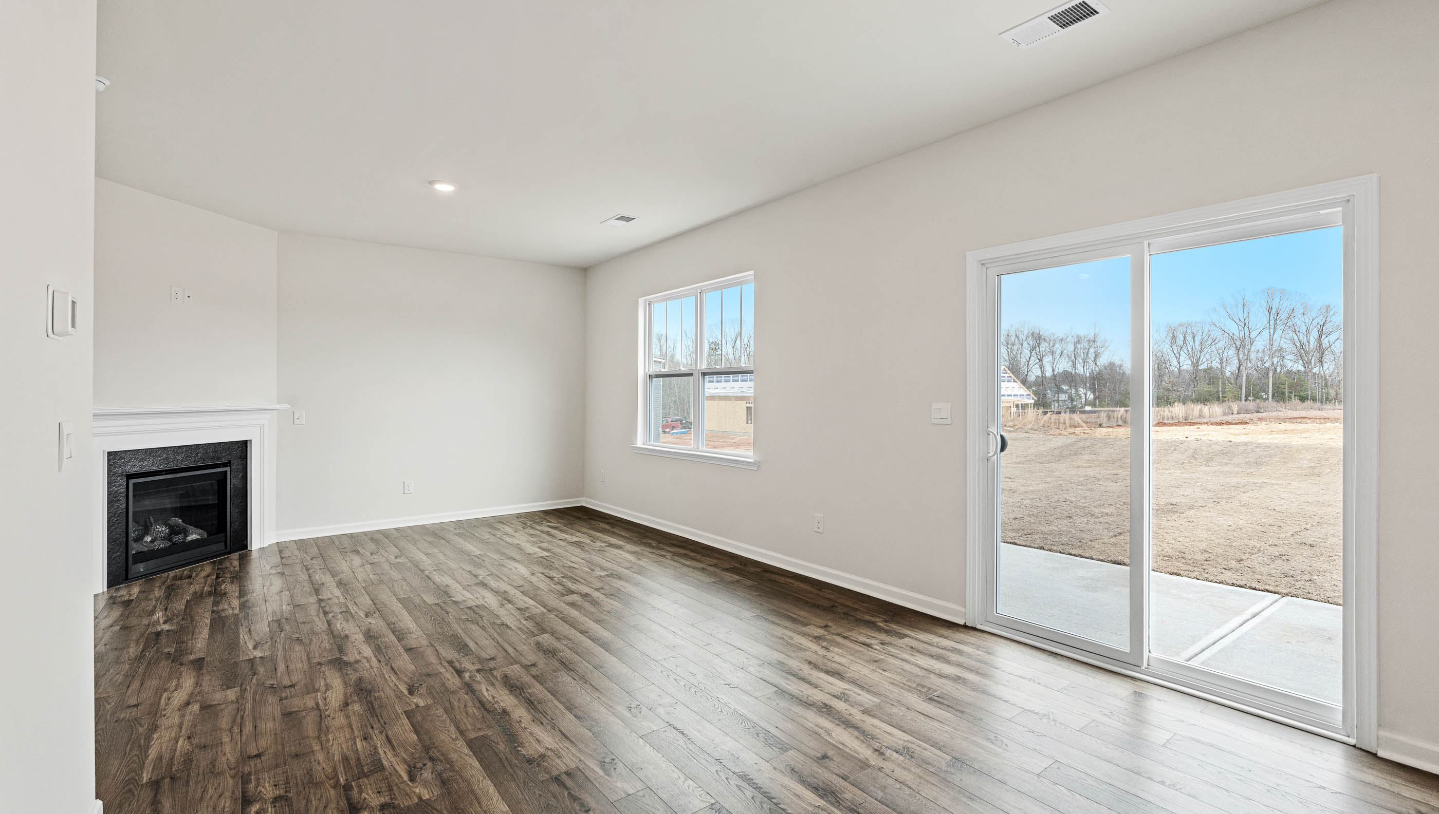 Living room with wood floors, fireplace, large window and sliding glass back door