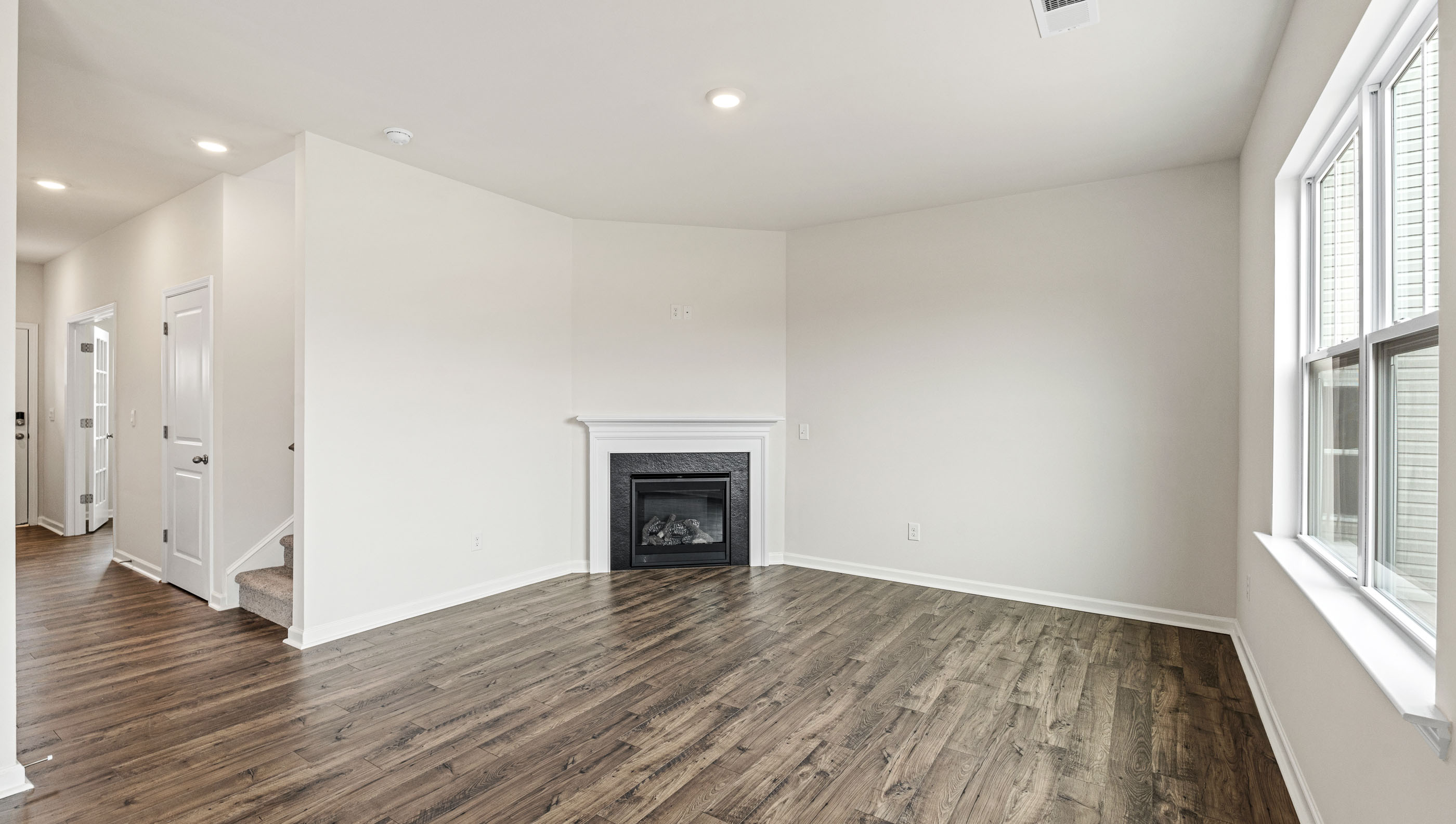 Living room with wood floors, fireplace, large window and sliding glass back door