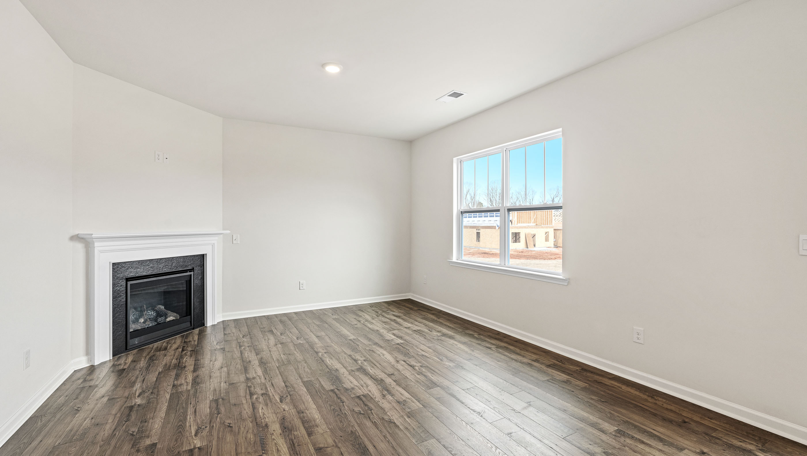 Living room with wood floors, fireplace, large window and sliding glass back door