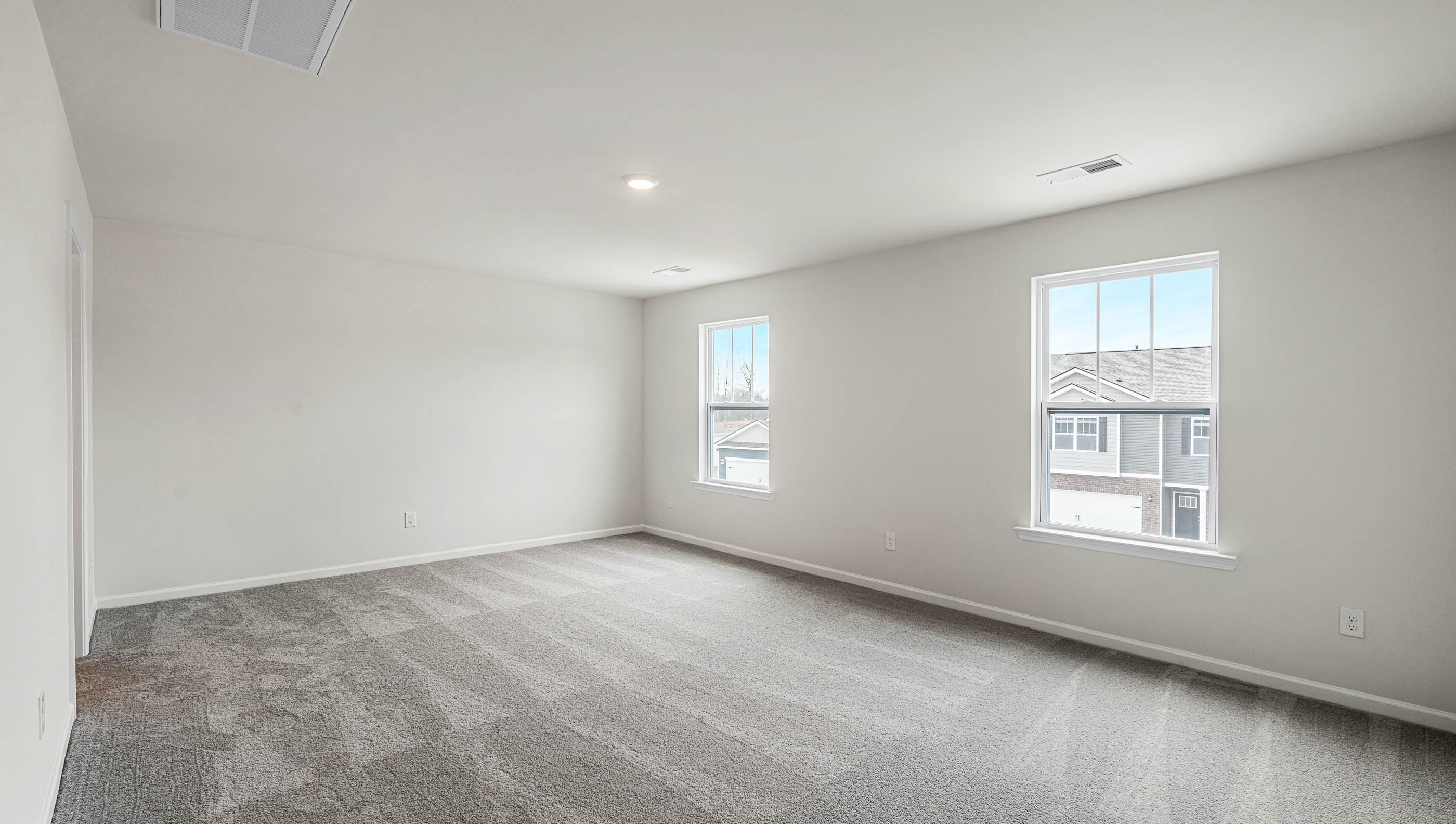 Primary bedroom with carpet and two large windows