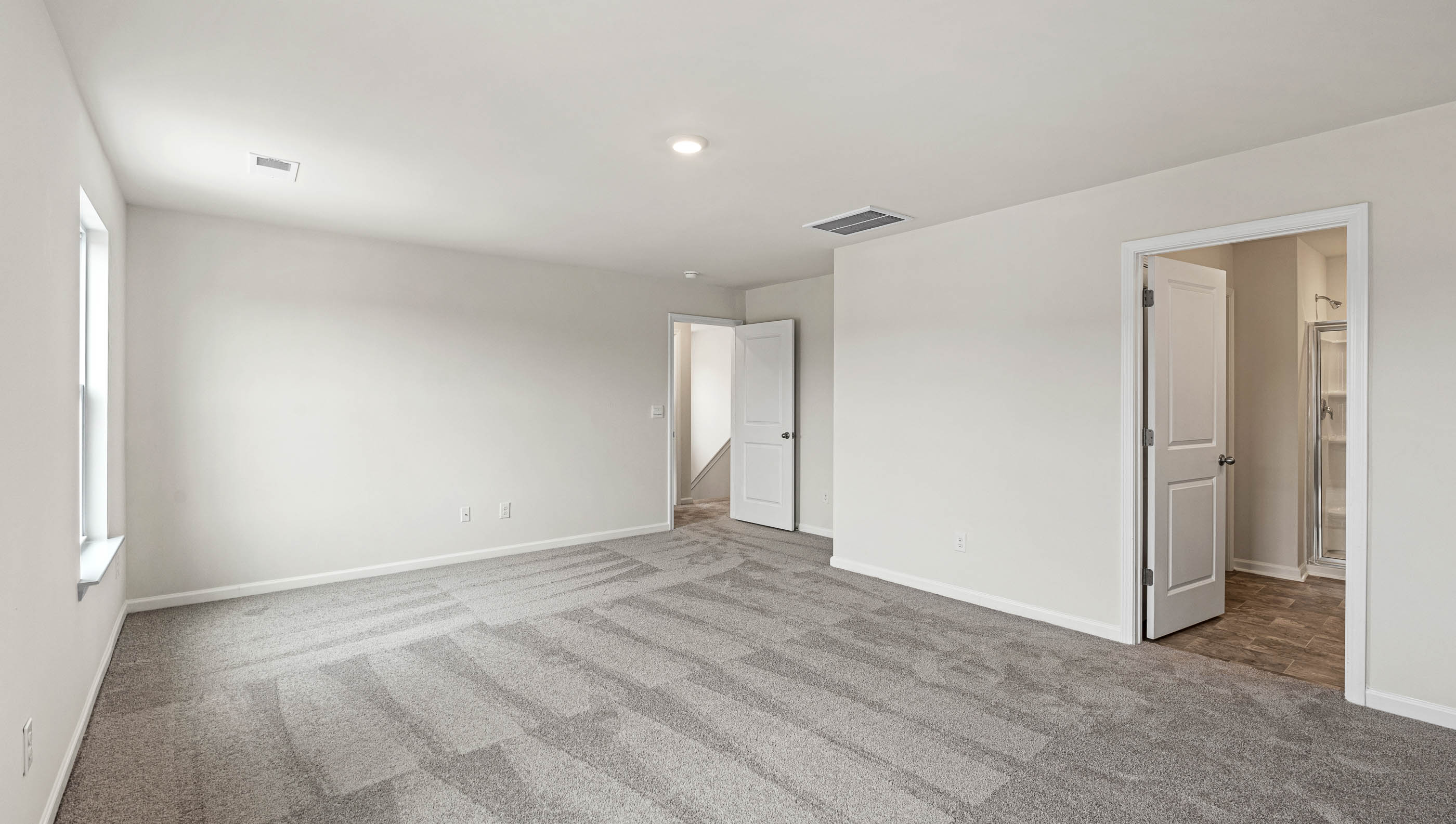 Primary bedroom with carpet and view of bathroom door and entryway door