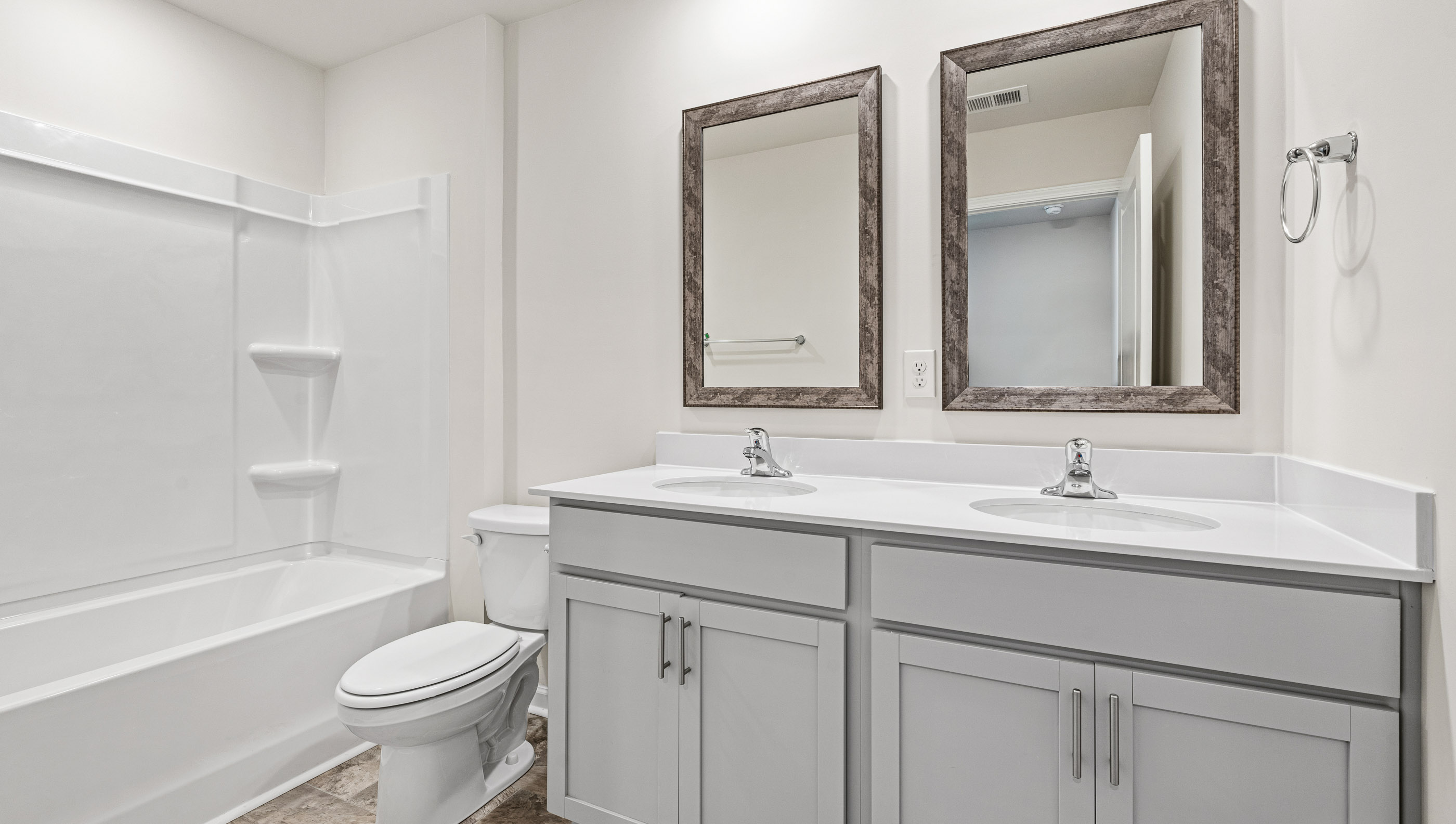 Bathroom with double sinks, bathtub, white cabinets and counters