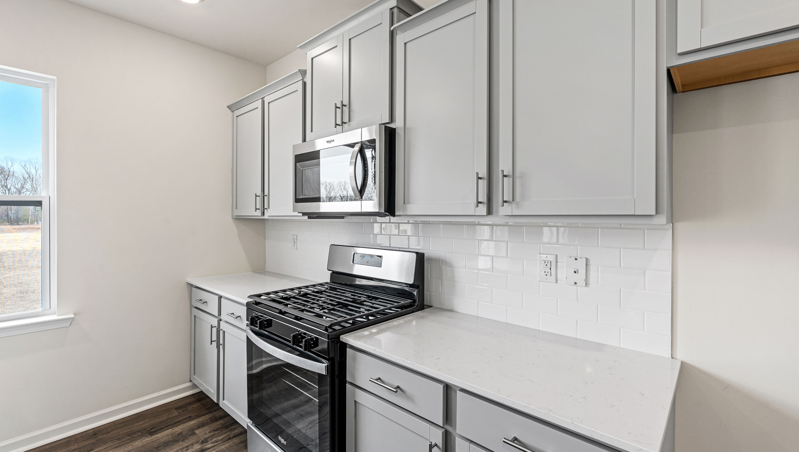 Kitchen and island with white cabinets and counters, wood floors and stainless steel appliances