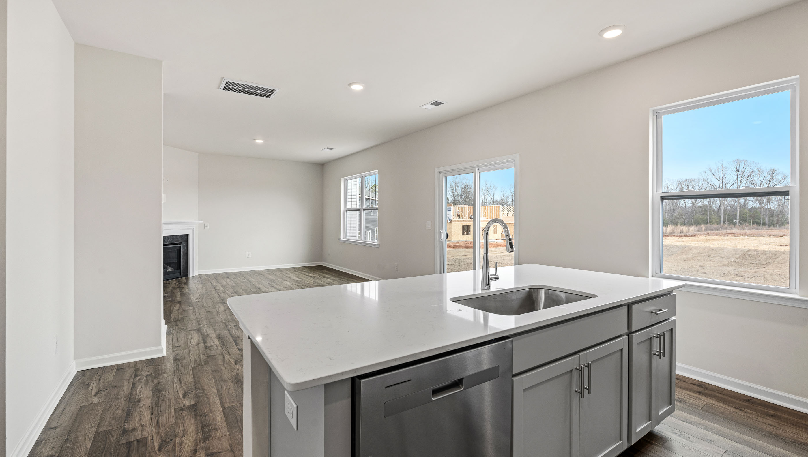 Kitchen and island with white cabinets and counters, wood floors and stainless steel appliances