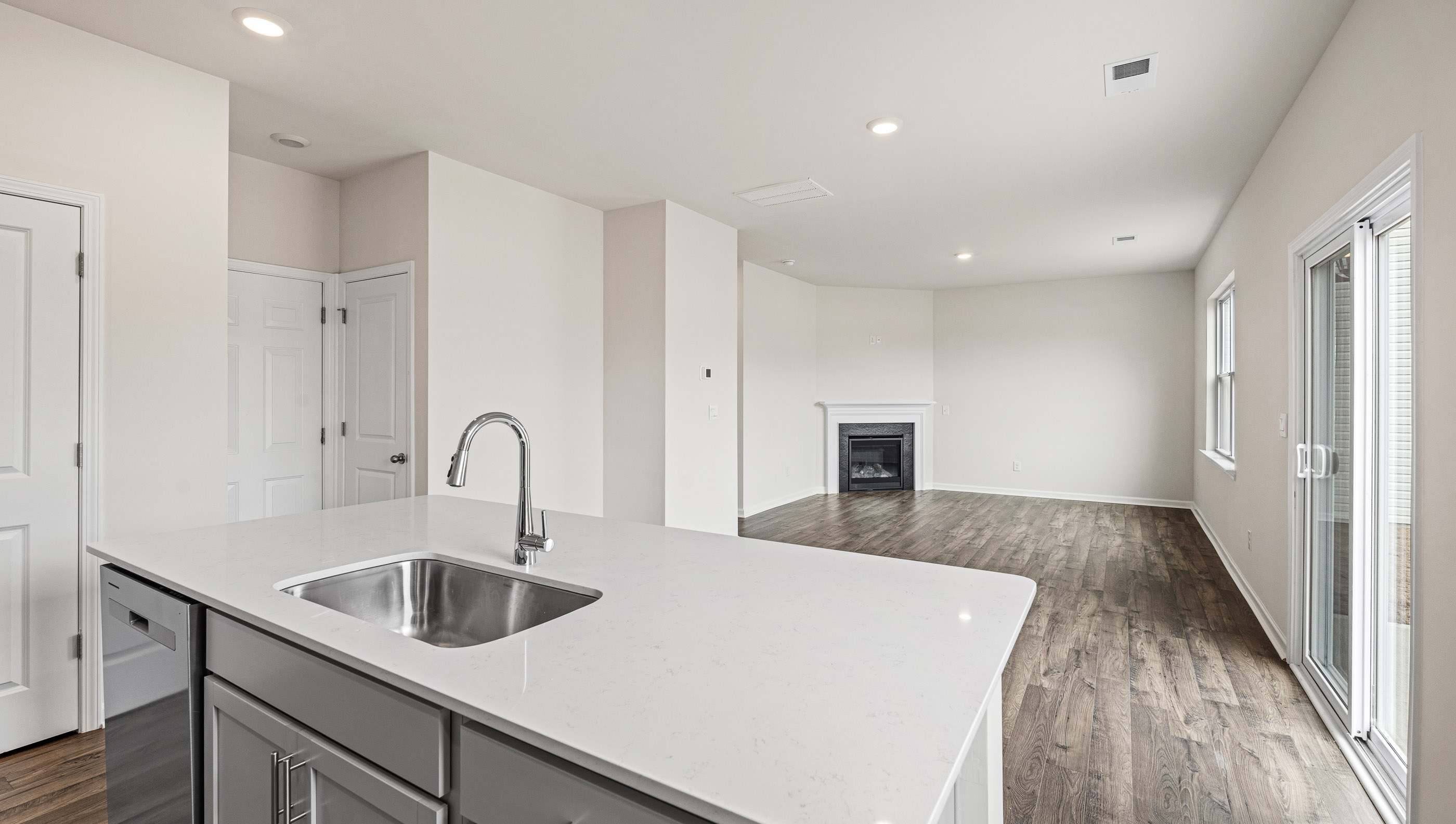 Kitchen and island with white cabinets and counters, wood floors and stainless steel appliances