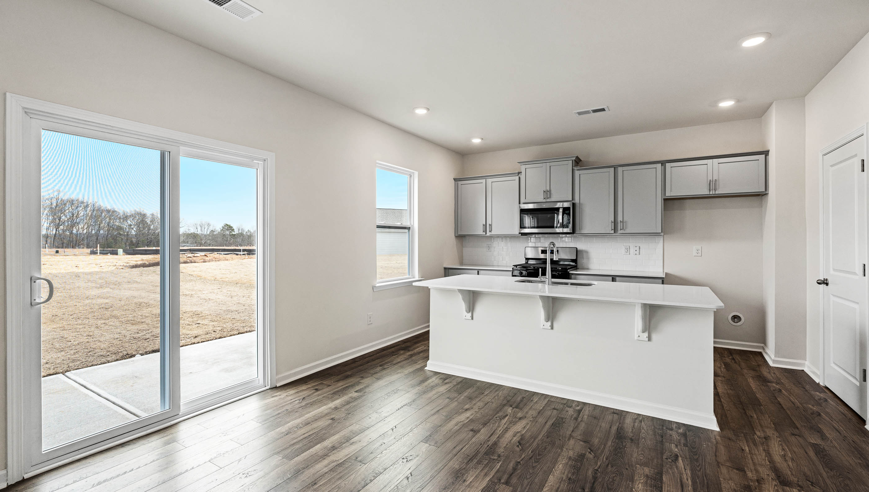 Kitchen and island with white cabinets and counters, wood floors and stainless steel appliances