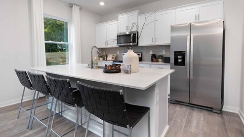 Kitchen and island with white cabinets and counters, vinyl floors and stainless steel appliances, New home near Charlotte, NC