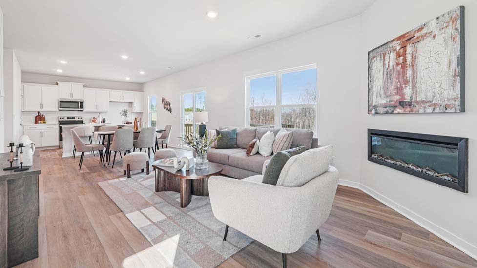 Open great room  beside kitchen, against staircase, with large window