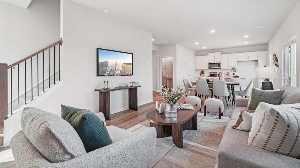 Open great room  beside kitchen, against staircase, with large window