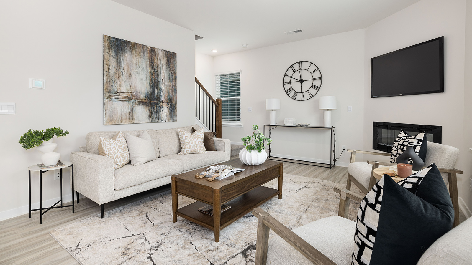 Open great room  beside kitchen, against staircase, with large window
